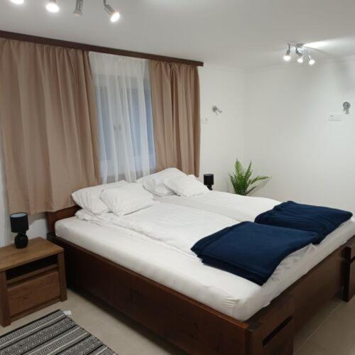um quarto com uma cama grande com lençóis brancos e azuis em Fakapu Vendégház em Sárospatak