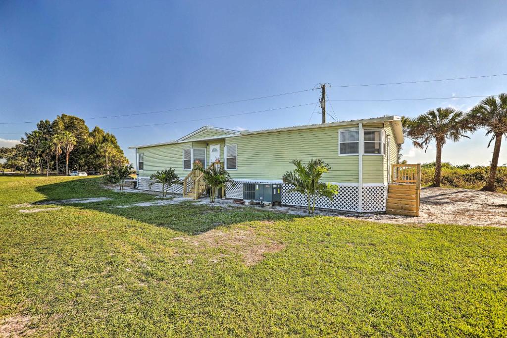 a green house with palm trees in front of it at Pet-Friendly Home 10 Mi to Lake Okeechobee! in Clewiston