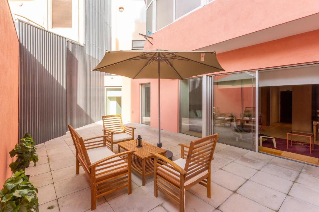a patio with a table and chairs and an umbrella at Garça Real Flats in Porto