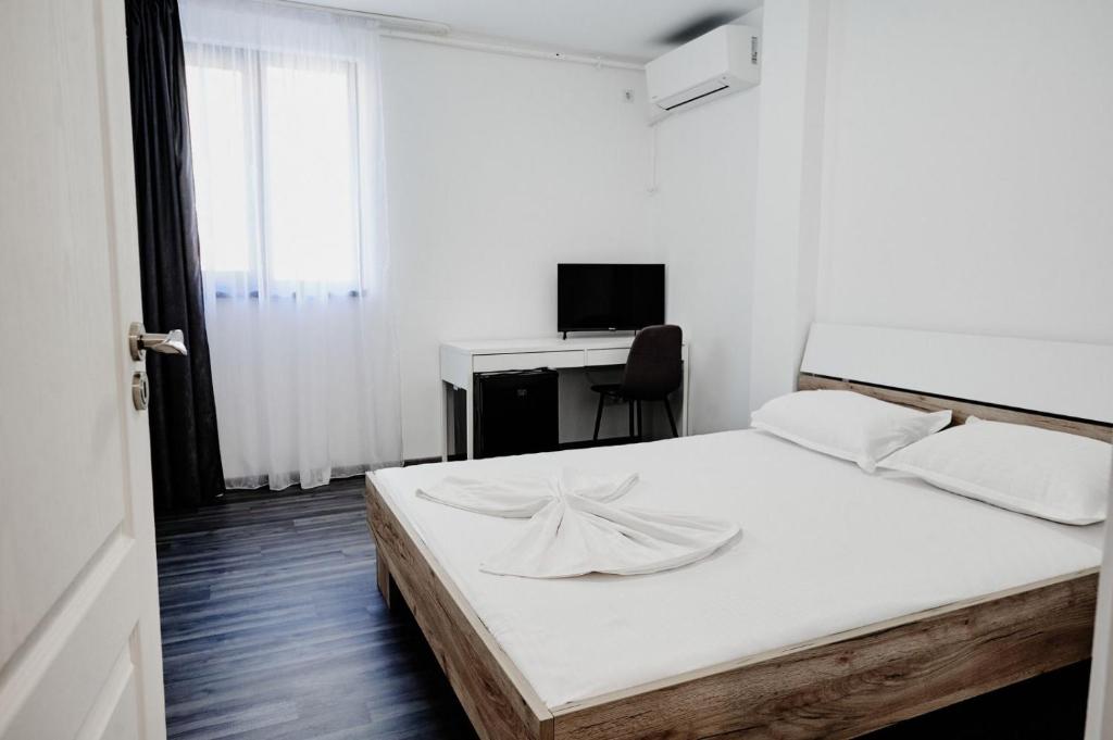 a white bedroom with a bed and a desk at Casa Adan in Drobeta-Turnu Severin