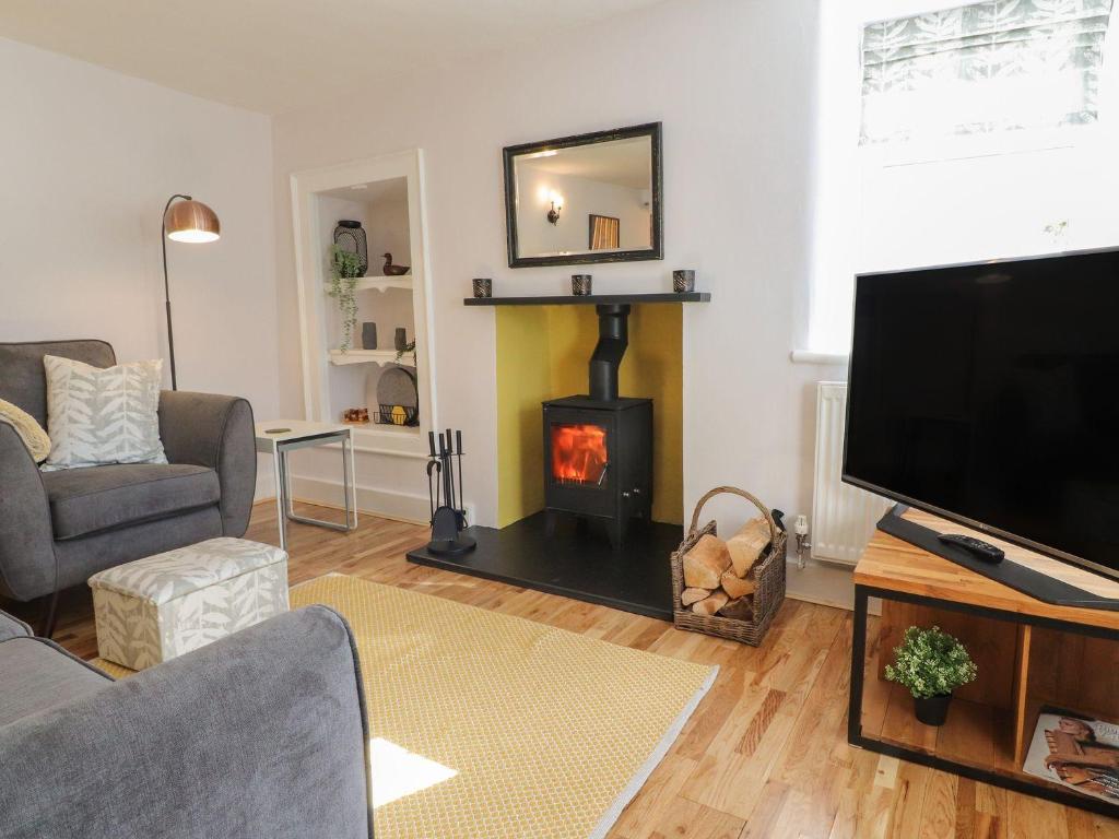 a living room with a fireplace and a tv at Rose Cottage in Clitheroe