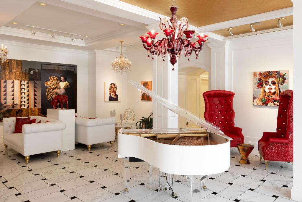 a living room with a white piano and red chairs at The Vendue, Downtown Art Hotel in Charleston