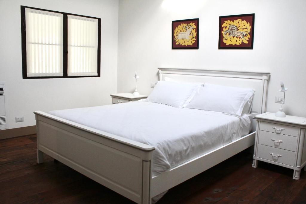 ein weißes Schlafzimmer mit einem Bett und zwei Fenstern in der Unterkunft Villa Trieste M in Asolo