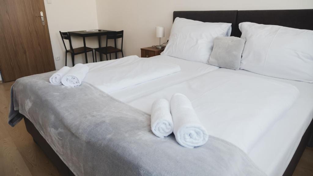 a large white bed with three rolled towels on it at Hotel U Ševce in Zlín