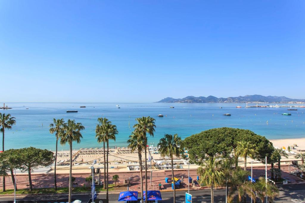 une vue sur une plage avec des palmiers et l'océan dans l'établissement REF 1196 - Cannes Croisette - Sea view apartment for rent, à Cannes