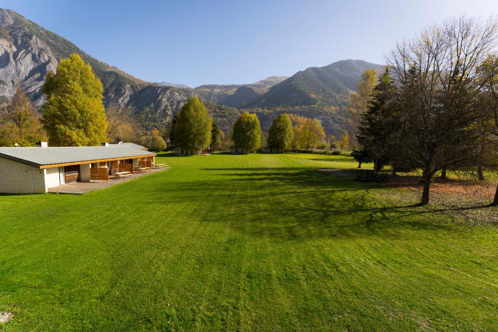 a house in a field with mountains in the background at Gite le Grand Renaud in Le Bourg-dʼOisans