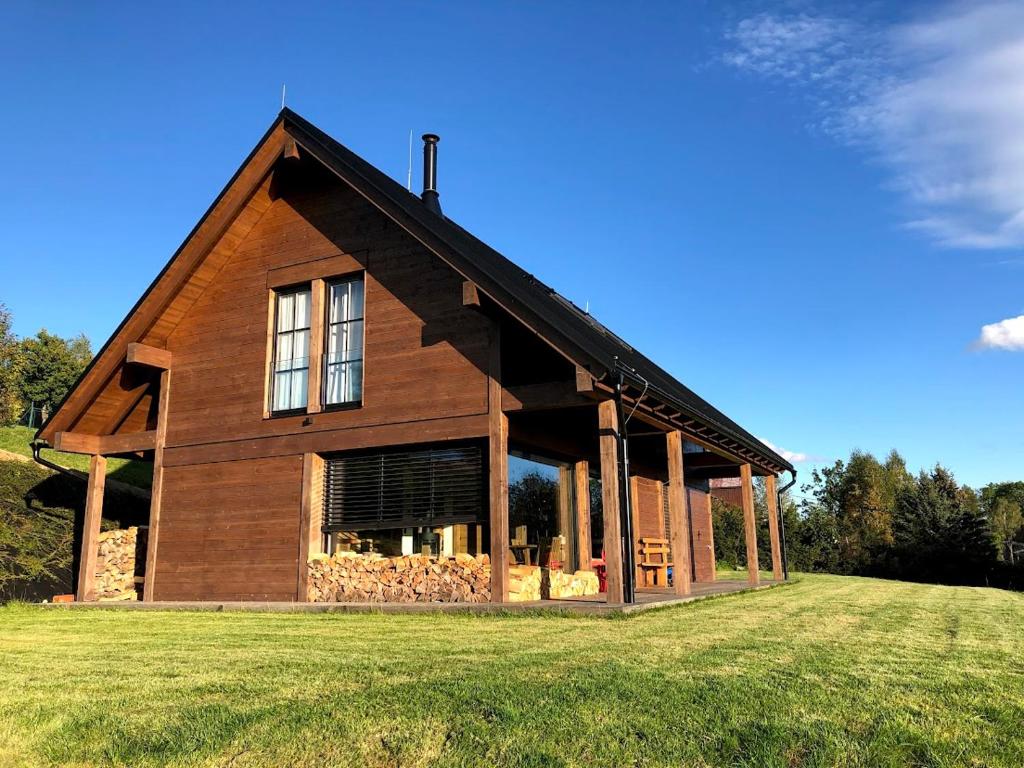 a large wooden house on a grass field at Mountain chalet in Kořenov