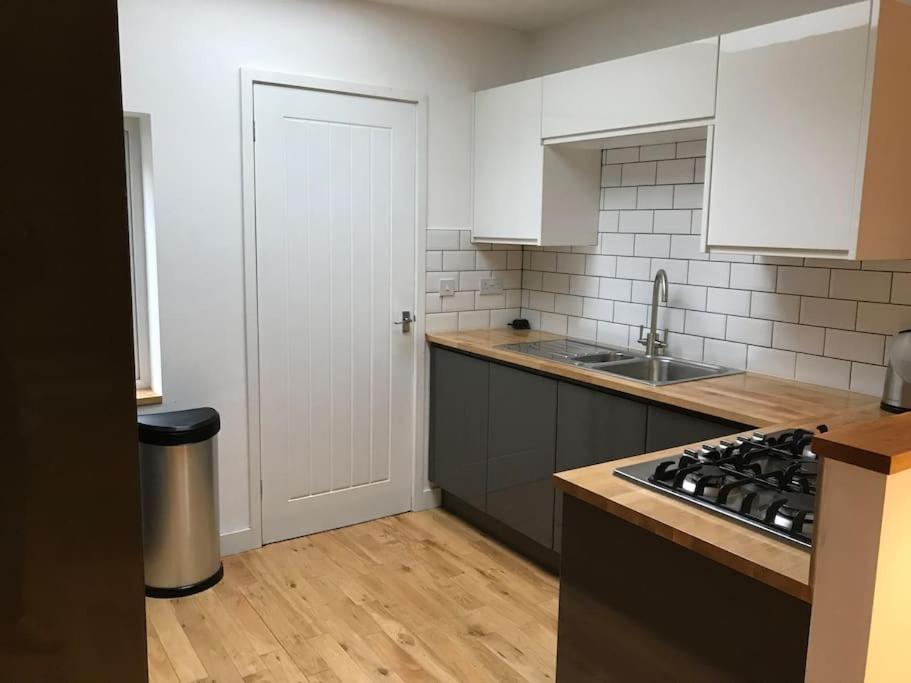 a kitchen with white cabinets and a stove top oven at City Center House, Cardiff, parking permit and garden in Cardiff