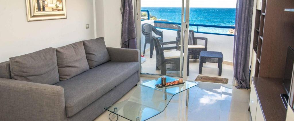 een woonkamer met een bank en een glazen tafel bij Beach front apartment in Playa Paraiso, PP70 in Playa Paraiso