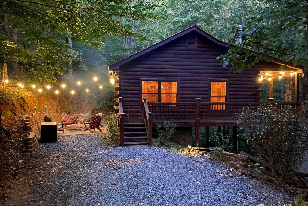 une cabane en rondins dans les bois la nuit avec des lumières dans l'établissement Bigfoots Hideout in Blue Ridge with Hot Tub!, à Blue Ridge