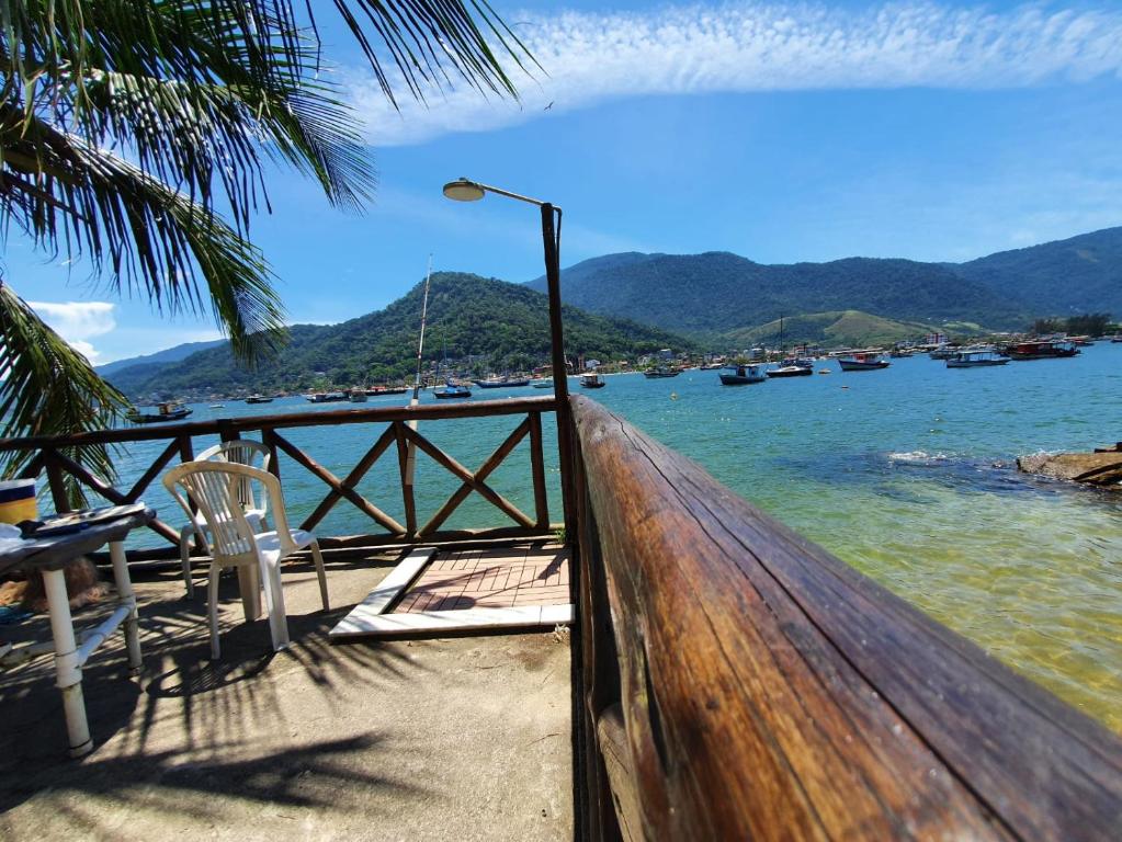 una valla de madera con una mesa y una silla junto al agua en A Casa da Ilha de Itacuruçá - Aps en Flecheiras
