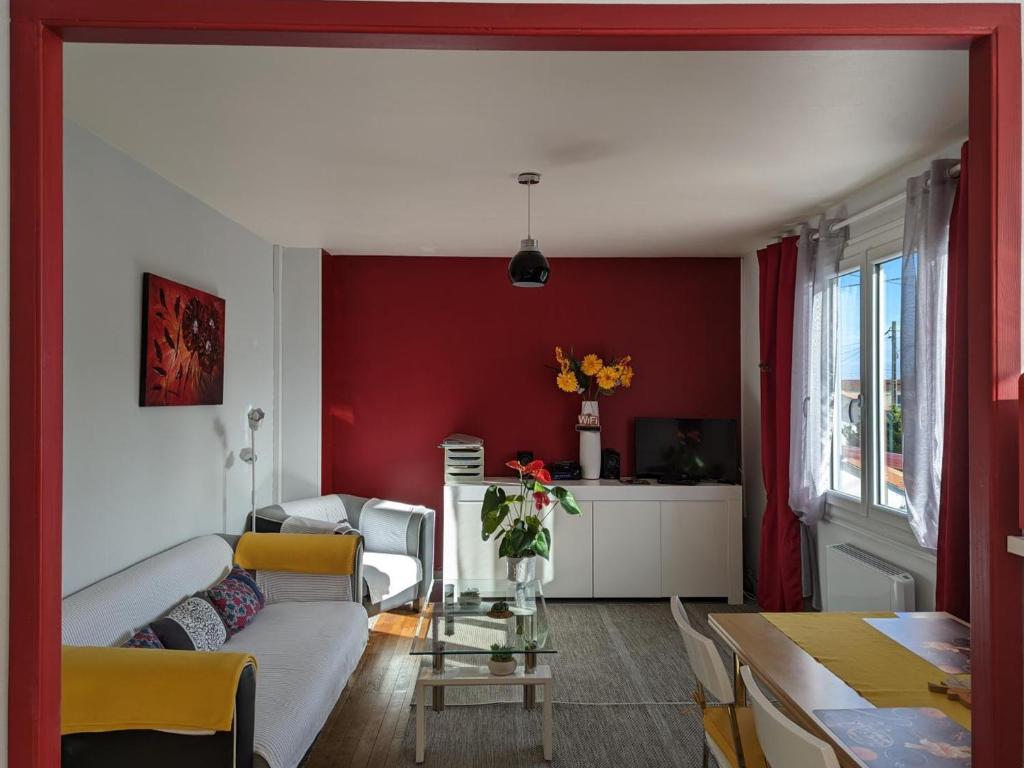 un soggiorno con divano bianco e parete rossa di Appartement cosy avec terrasse et jardin privatif, à 5 min du centre-ville de Barbezieux. - FR-1-653-196 a Barbezieux-Saint-Hilaire