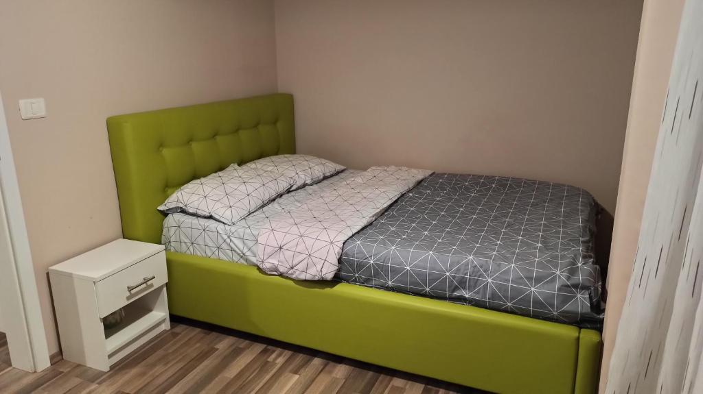 a bed with a green headboard in a room at Cozy home Bujorilor in Timişoara