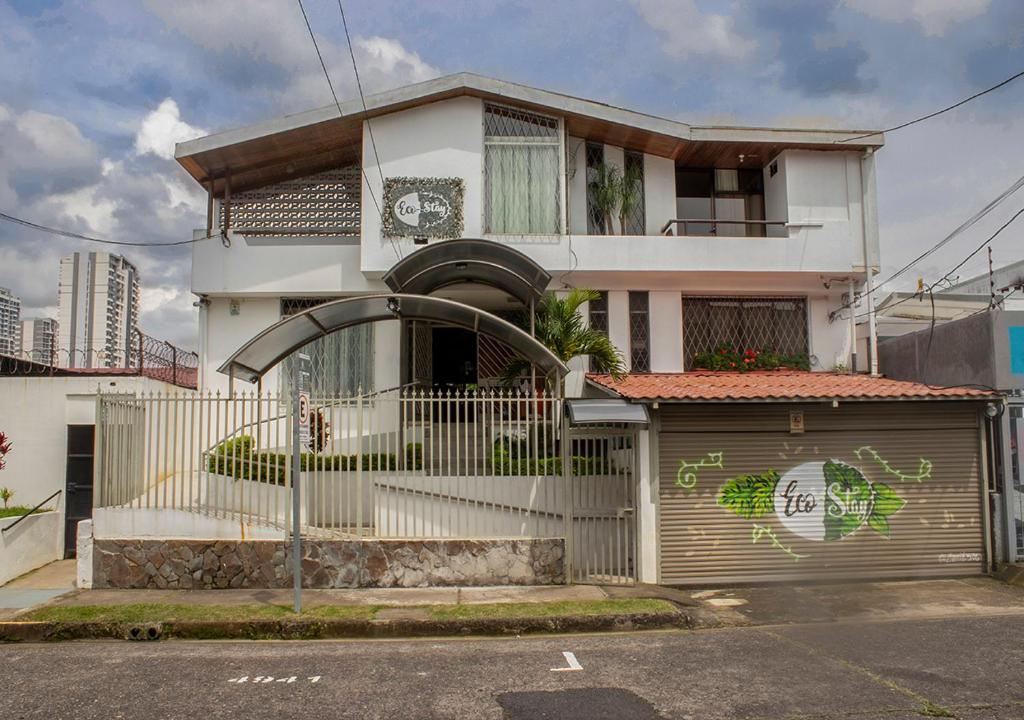 una casa blanca con una puerta y una valla en Eco Stay Hostel, en San José