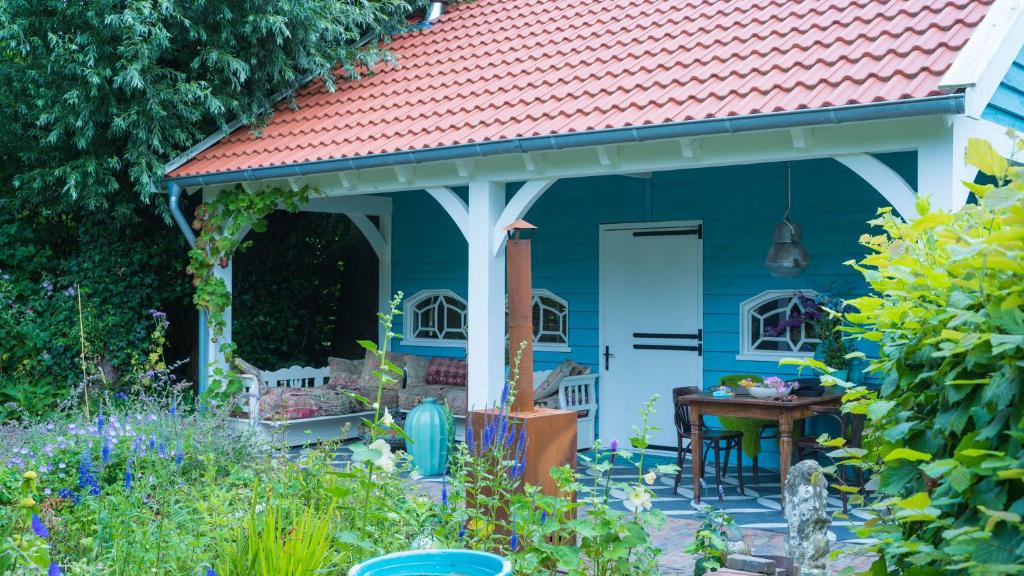 ein blaues Cottage mit rotem Dach im Garten in der Unterkunft Wonderland in Pieterburen