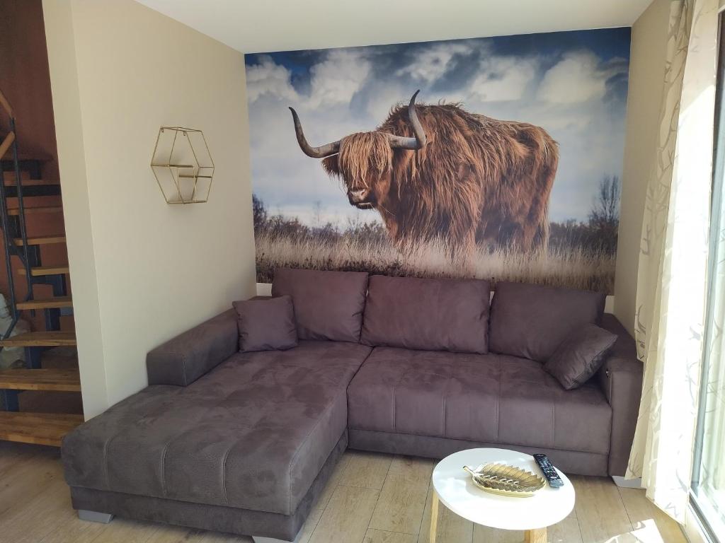 - un canapé dans le salon orné d'une peinture sur une vache dans l'établissement Ferienhof-Dachsberg Wohnung Highlander, à Bermatingen