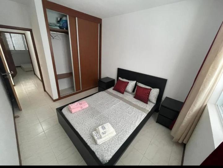 a room with a bed with red pillows on it at Apartamento Vila Santa Bárbara ,Bloco F RChão Esq,Santo Antão,Cabo Verde in Mão para Trás