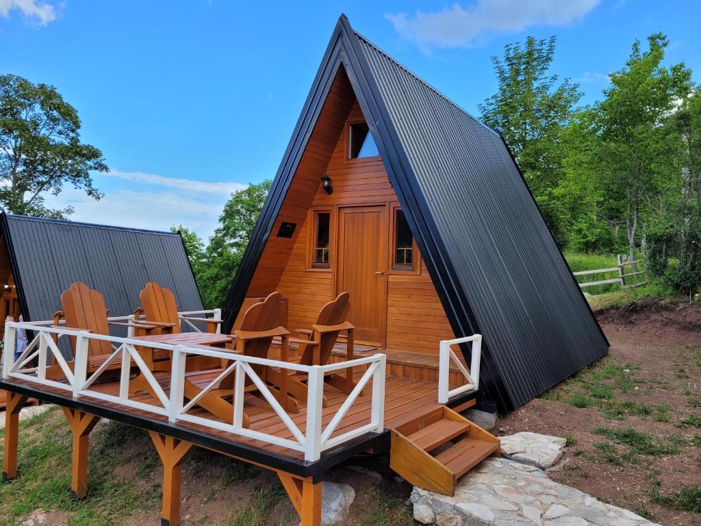 une cabane en rondins avec une terrasse et des chaises dans l'établissement Koliba Umoljani, à Umoljani