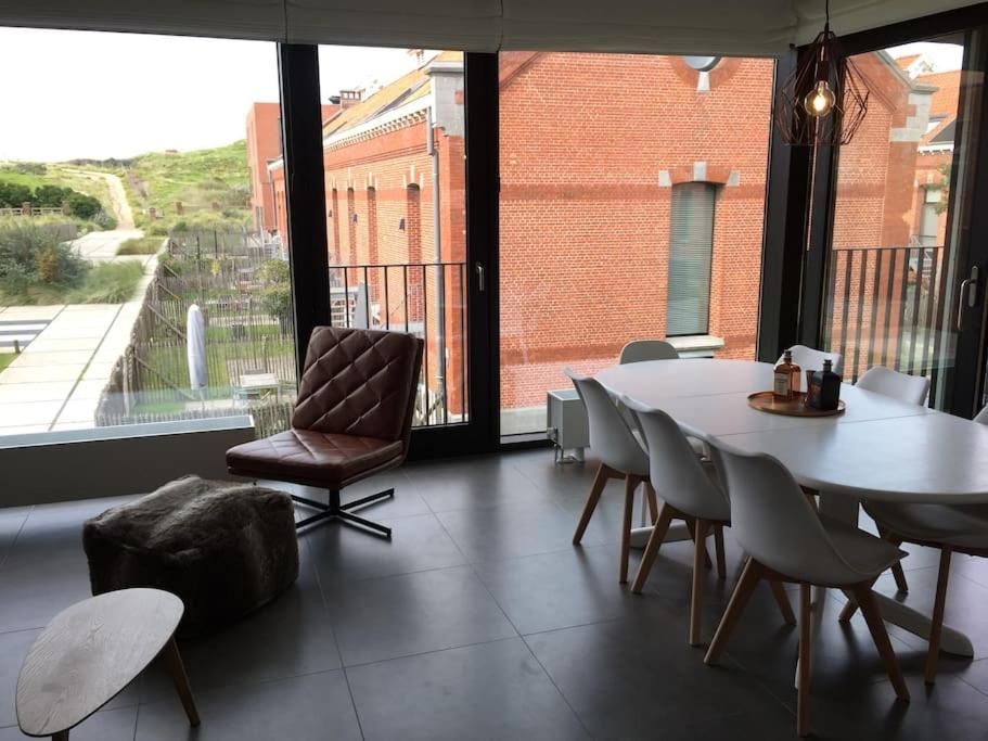 オーステンデにあるHedendaags, verzorgd appartement op unieke locatieのダイニングルーム(テーブル、椅子付)、大きな窓が備わります。