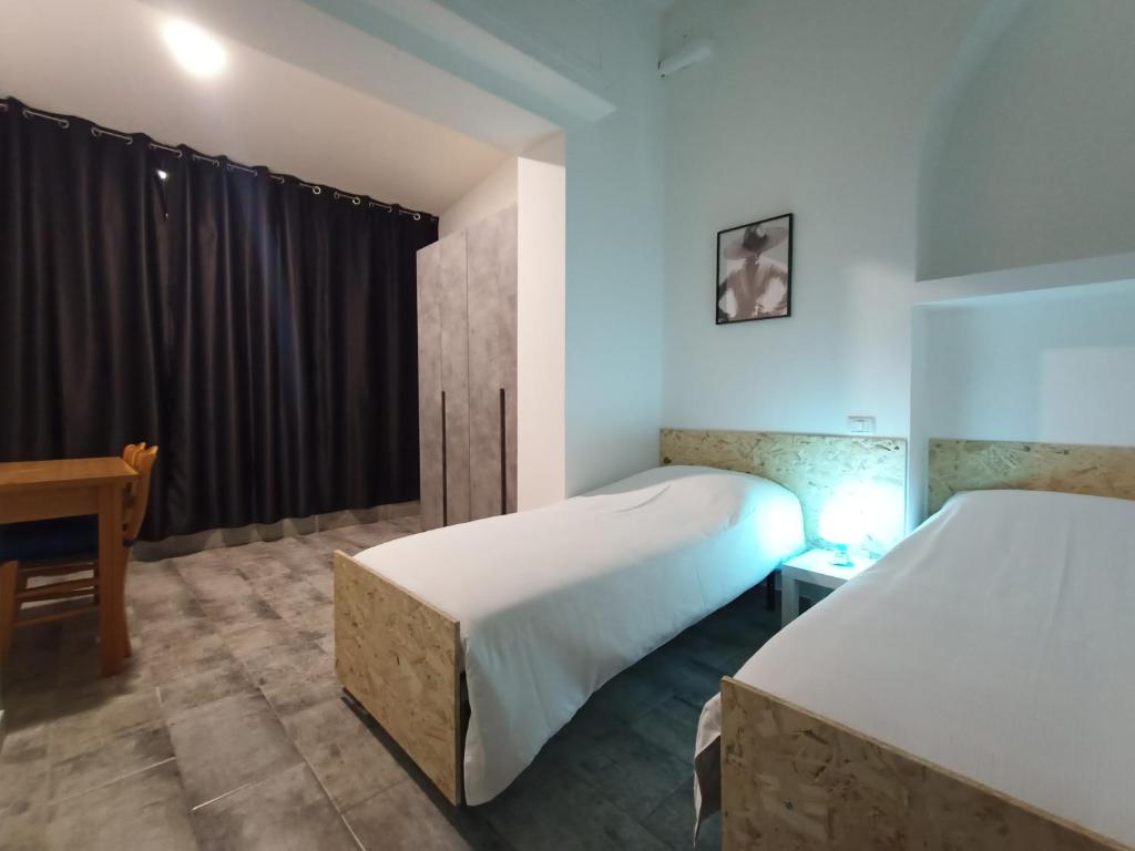 a bedroom with two beds and a desk and a window at Airport Boulevard Guesthouse in Grassobbio