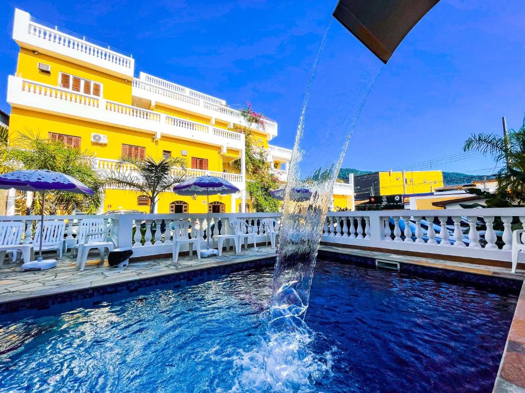 uma fonte numa piscina em frente a um edifício amarelo em Hotel Parque Atlântico em Ubatuba