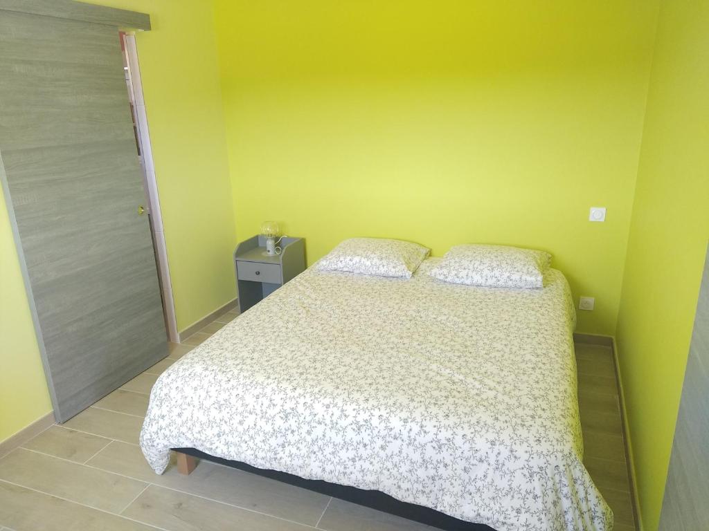 um quarto com uma cama e uma parede amarela em sasu eco nature em Vendays-Montalivet
