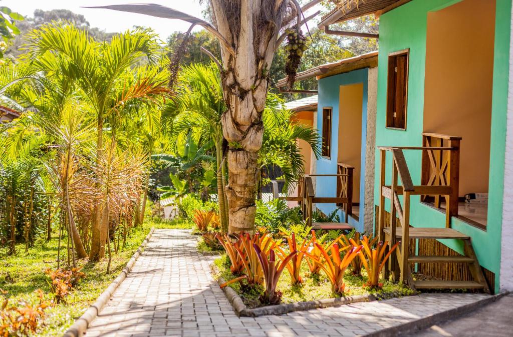 a house with a palm tree next to a sidewalk at Flats Brasil Itacaré in Itacaré