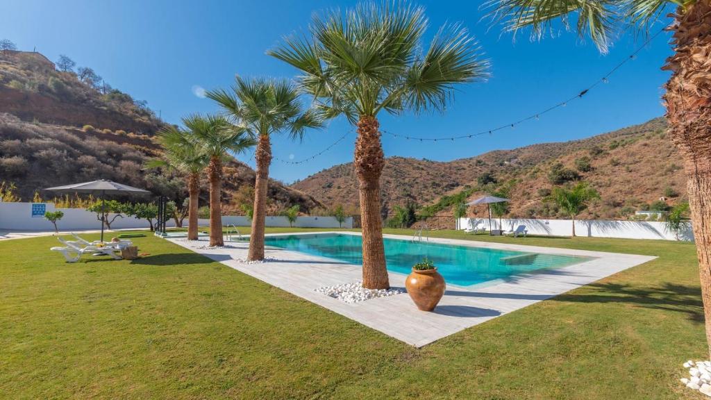 a swimming pool with palm trees in a yard at Casa Rural Era del Puerto Totalán by Ruralidays in Tolatán