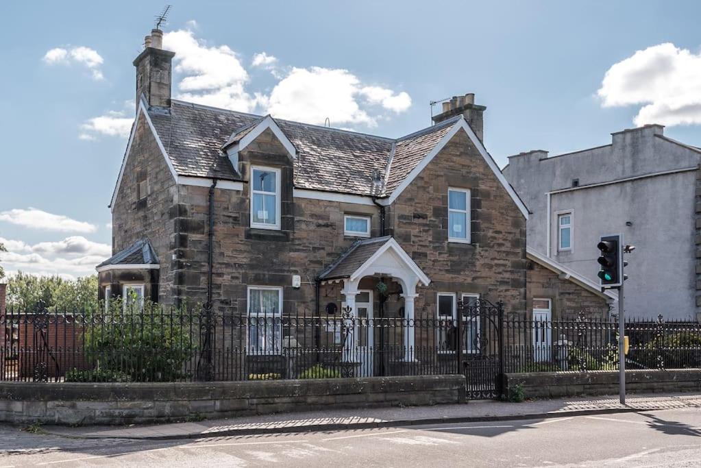 an old stone house with a fence and a traffic light at Abercorn Lodge Semi-Detached House in Edinburgh