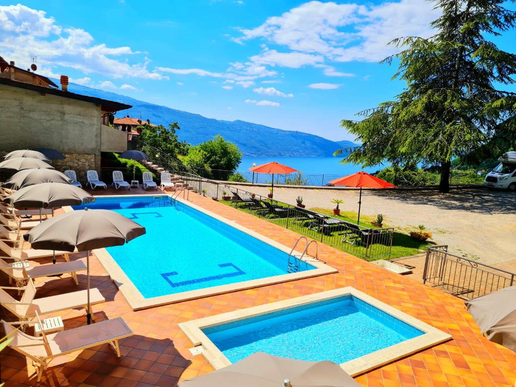 a swimming pool with chairs and umbrellas next to a resort at Residence Casa Silvana in Tignale