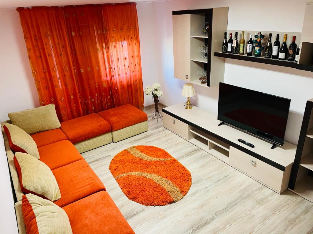 uma sala de estar com um sofá laranja e uma televisão de ecrã plano em Imperium DK Apartament em Giurgiu