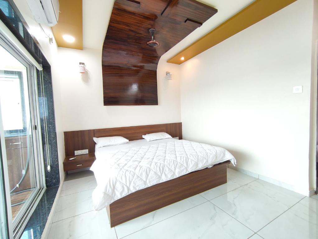 a bedroom with a bed with white sheets and wooden ceilings at Hotel Sardar Rooms in Garudeshwar