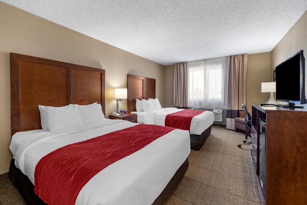 a hotel room with two beds and a flat screen tv at Comfort Inn & Suites Hays I-70 in Hays