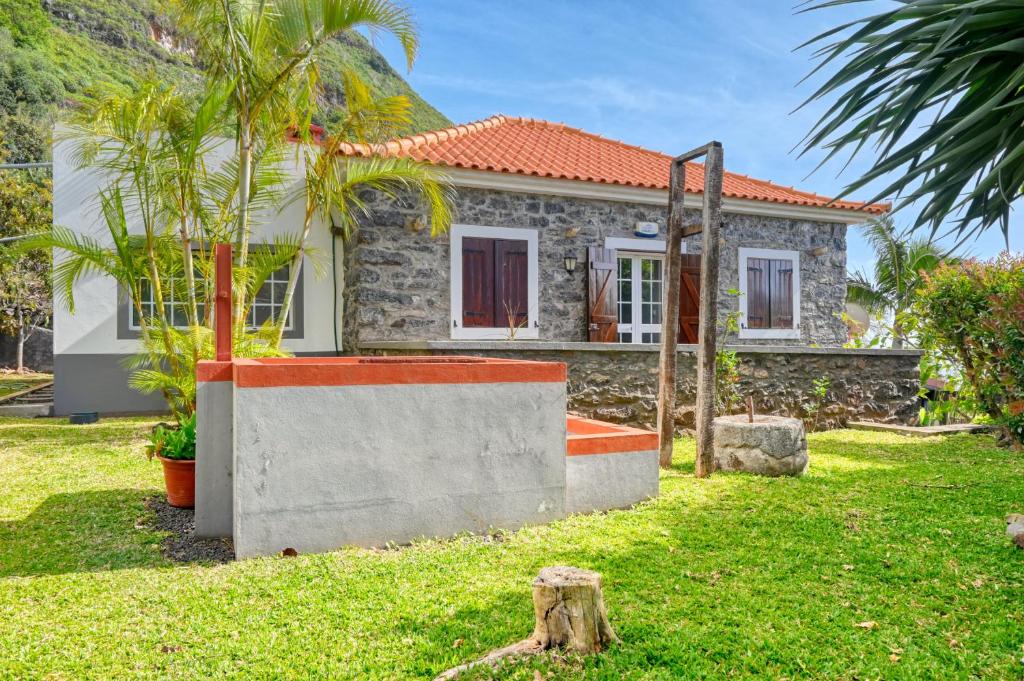a house with a palm tree in front of it at Casa do Pombal, a Home in Madeira in Arco da Calheta