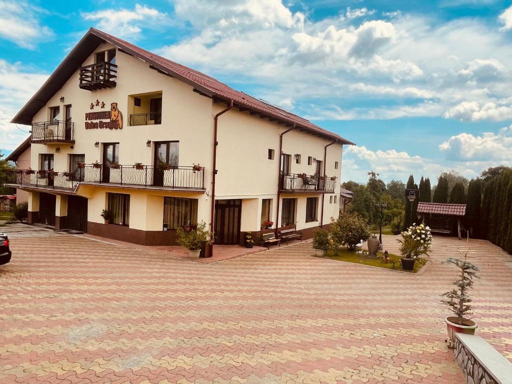 Un grand bâtiment blanc avec balcon et parking est disponible. dans l'établissement Pensiunea Valea Ursului, à Cîmpulung