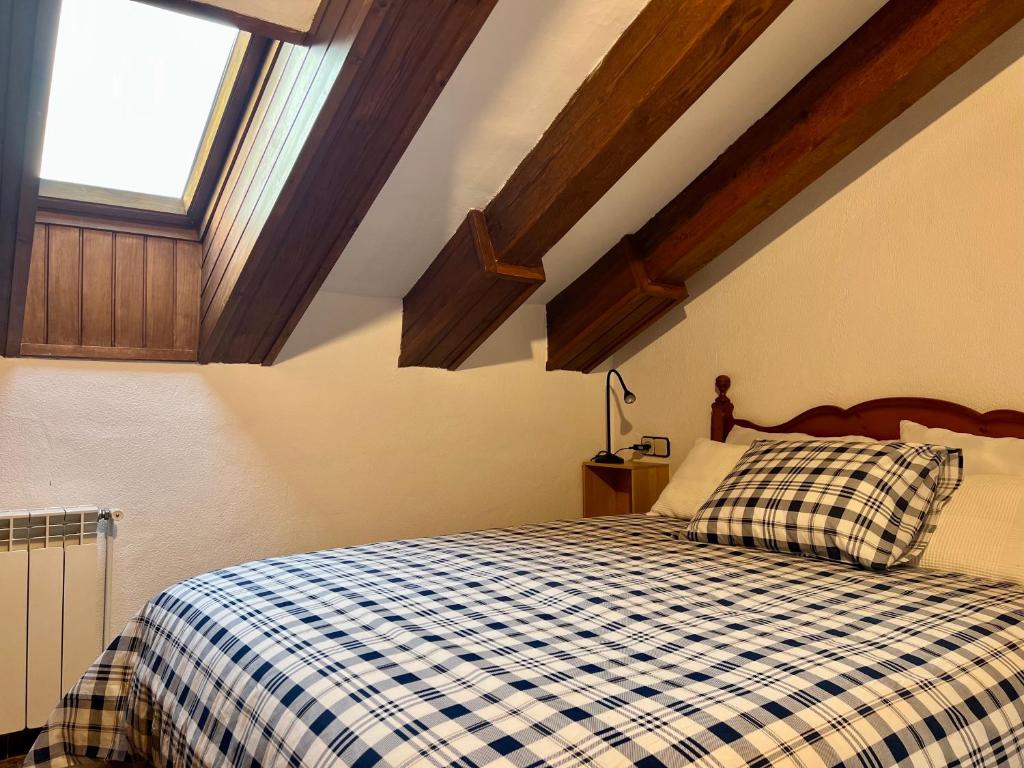 a bedroom with a bed with a checkered blanket at ÀTIC CASA POMAR in Camprodon