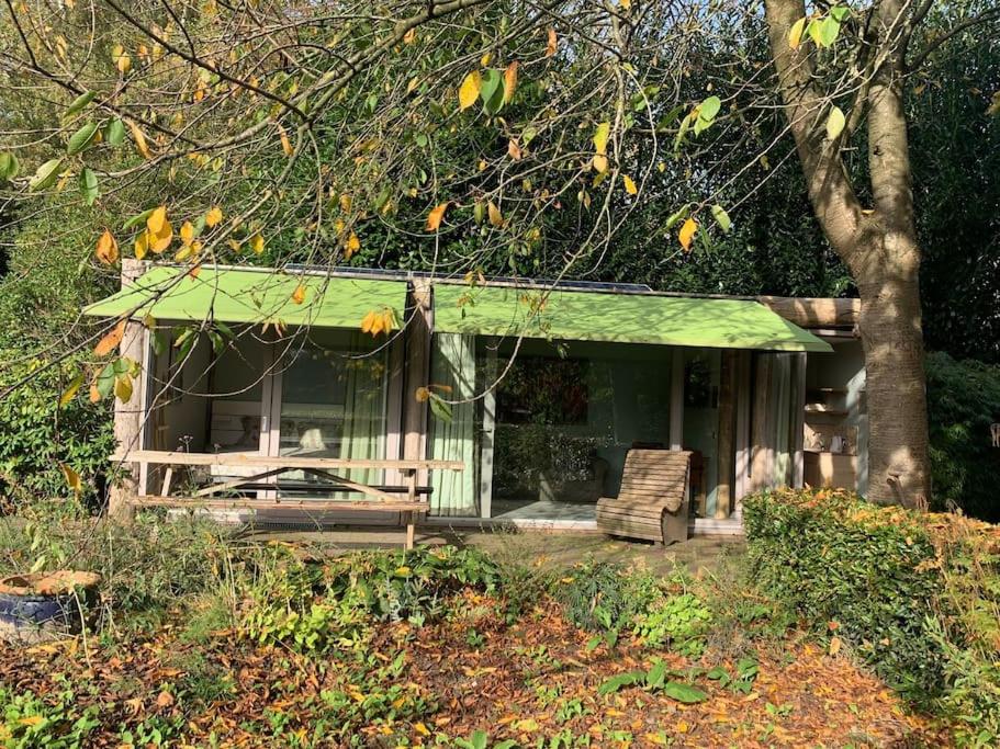 een huis met een groen dak en een stoel bij Tuinkamer met landelijk uitzicht en zwembad. in Berkel-Enschot