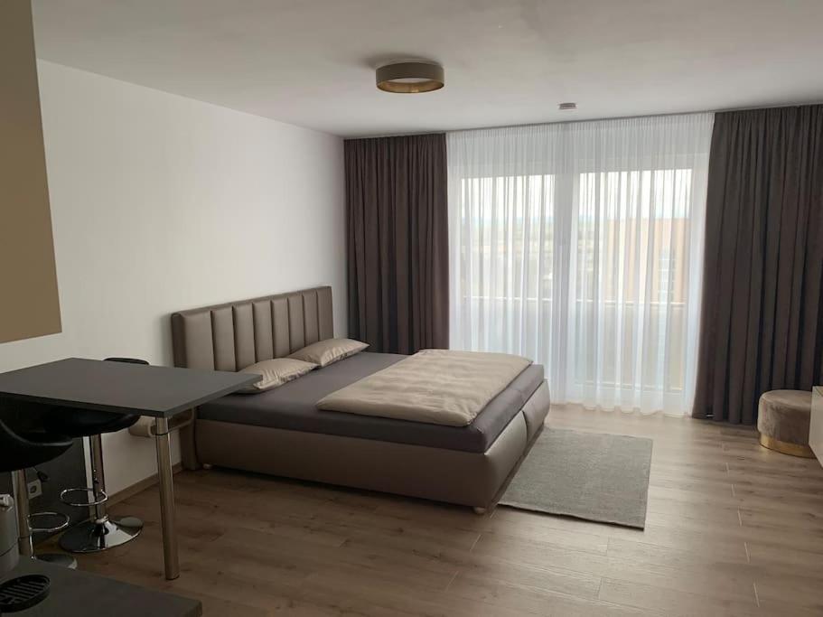1 dormitorio con cama, escritorio y ventana en Eine gemütliche Einzimmerwohnung en Ostfildern
