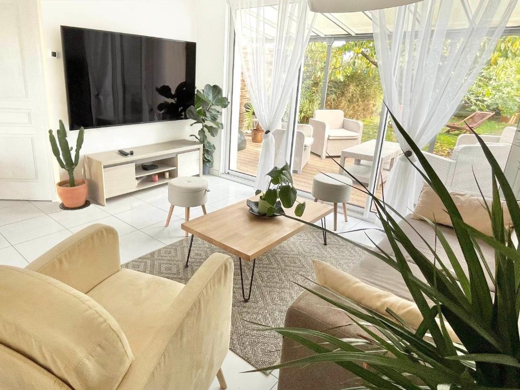 a living room with white furniture and a tv at Location maison Jardin Gîte Angers Les Ponts de Cé in Les Ponts-de-Cé