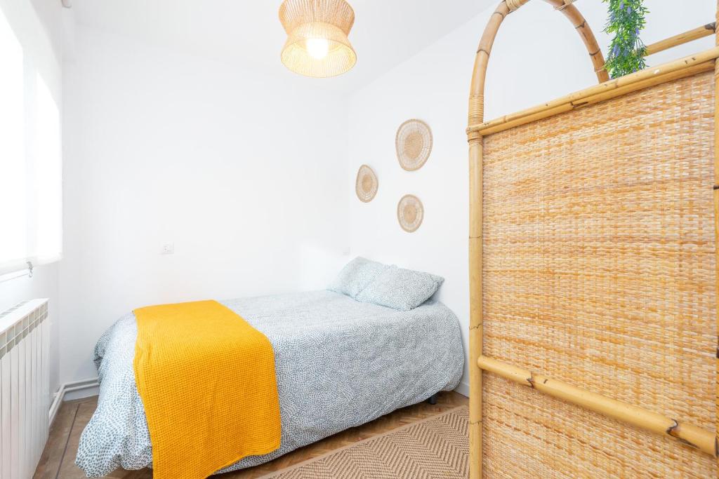 a bedroom with a bed and a wicker wall at De la cama a la mar in Luanco