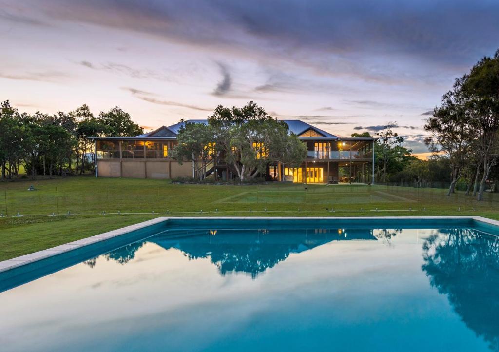 a house with a swimming pool in front of a house at Tranquilo Beach House in Woolgoolga