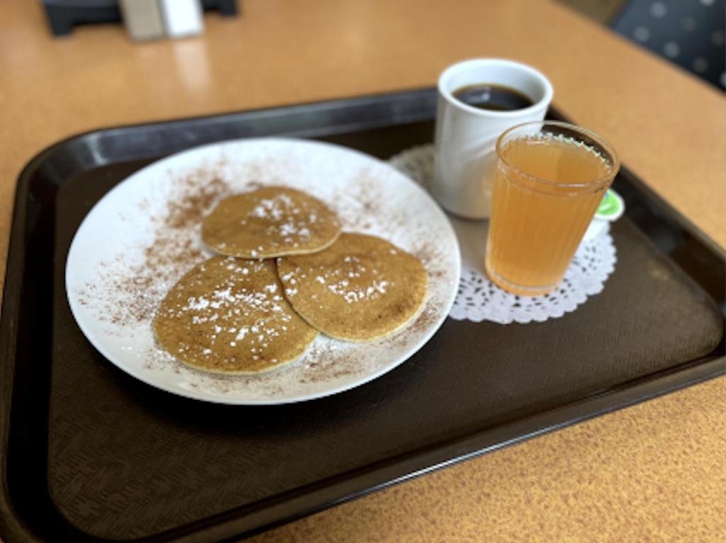 a tray with a plate of pancakes and a glass of juice at Carey Centre on UBC campus in Vancouver