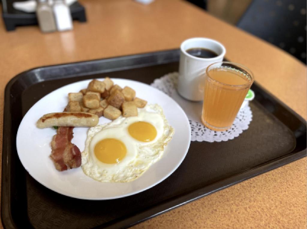 a tray with a plate of eggs and bacon and a glass of juice at Carey Centre on UBC campus in Vancouver