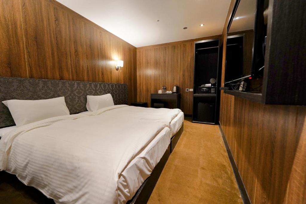 - une chambre avec un grand lit blanc et une télévision dans l'établissement Water meworld, à Taipei