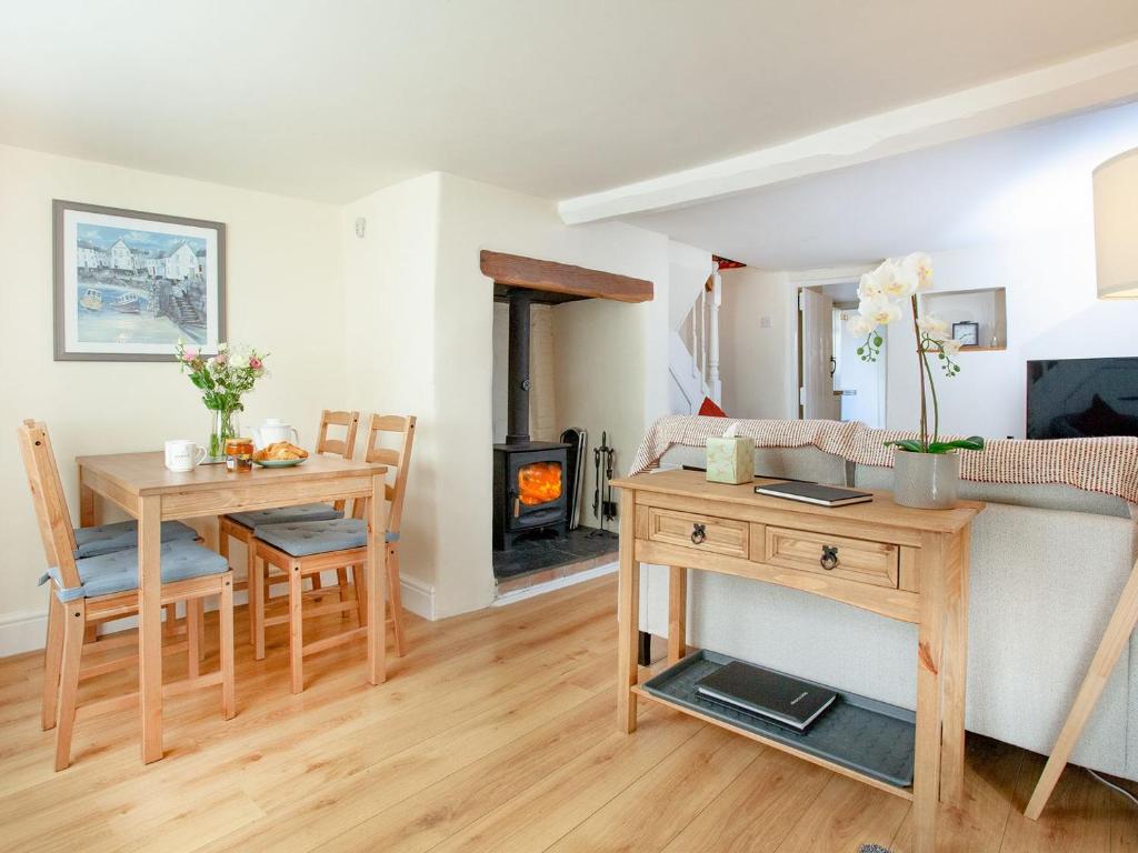 a living room with a table and a fireplace at Otters Cottage in Ottery Saint Mary