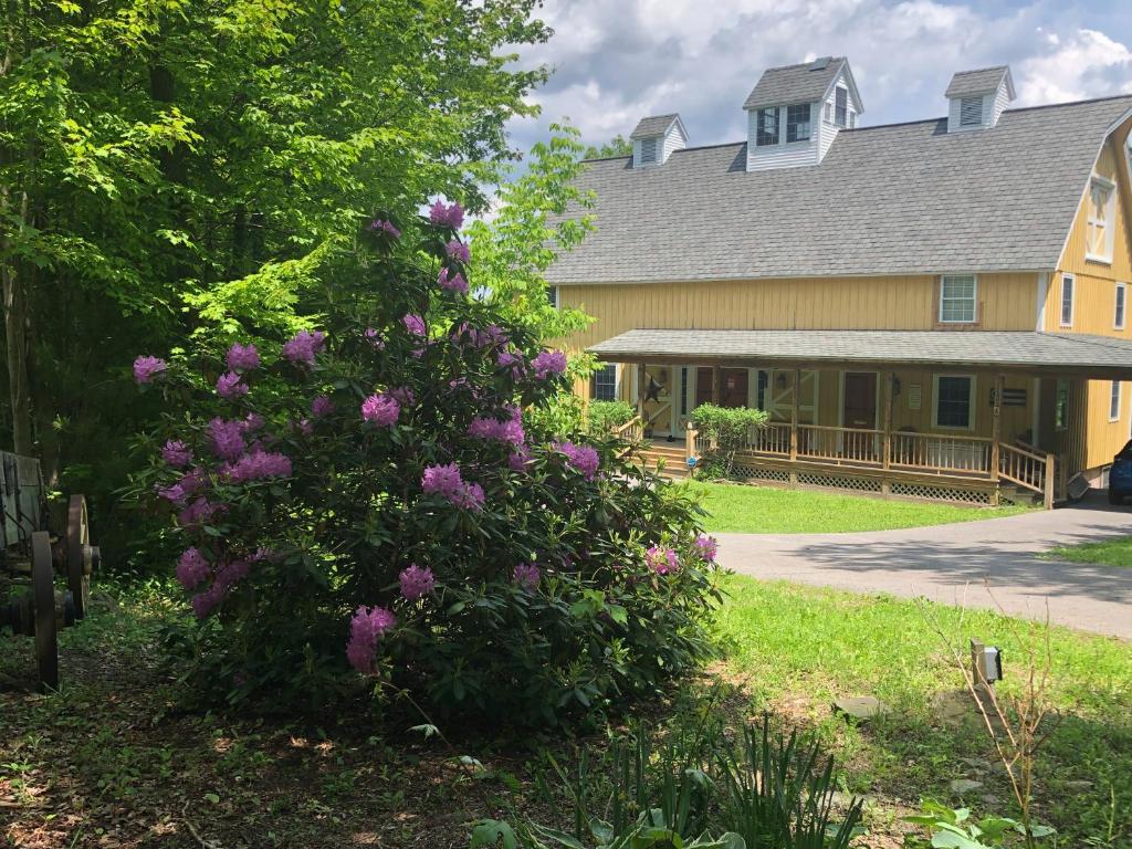 um arbusto com flores roxas em frente a uma casa em Yellow Barn Estate em Freeville