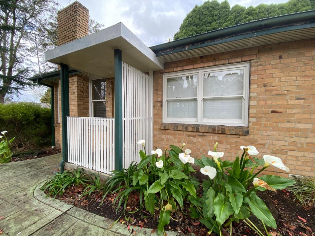 a brick house with a window and white flowers at Melbourne Mitcham Holiday Home in Mitcham