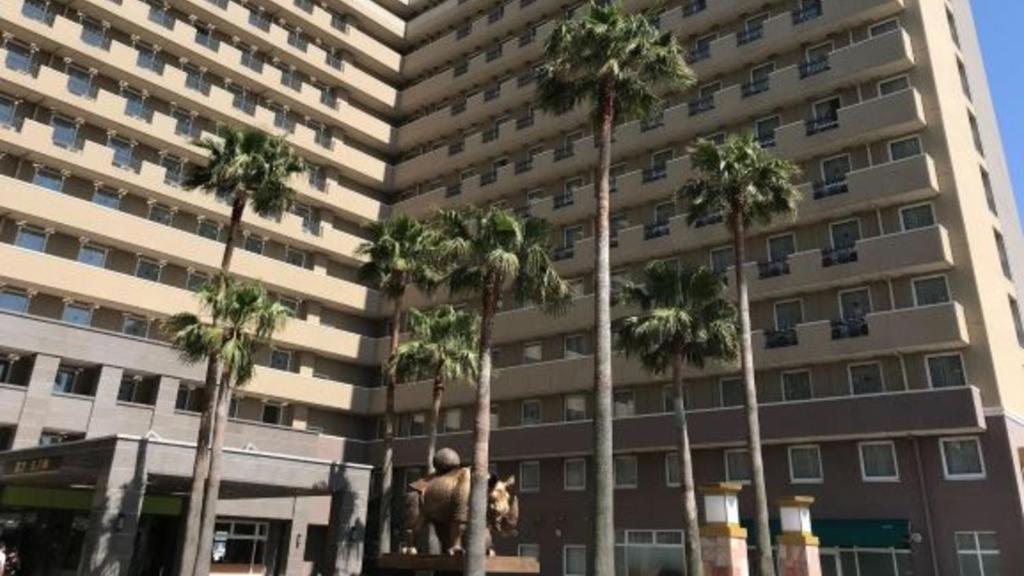 a large building with palm trees in front of it at Toyoko Inn Chubu International Airport No1 in Tokoname