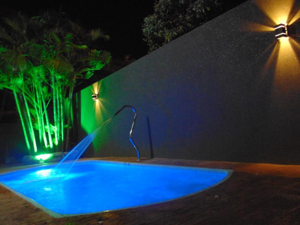 uma piscina azul com luz verde junto a uma parede em Casa Olímpia, piscina aquecida, ar condicionado, garagem 2 carros p em Olímpia