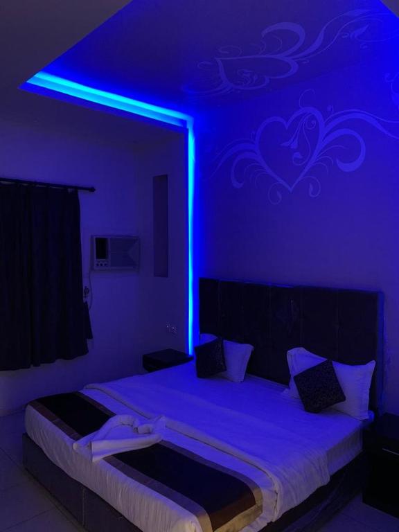 a bedroom with a bed with a blue light at ركن الهدوء in Muhayil